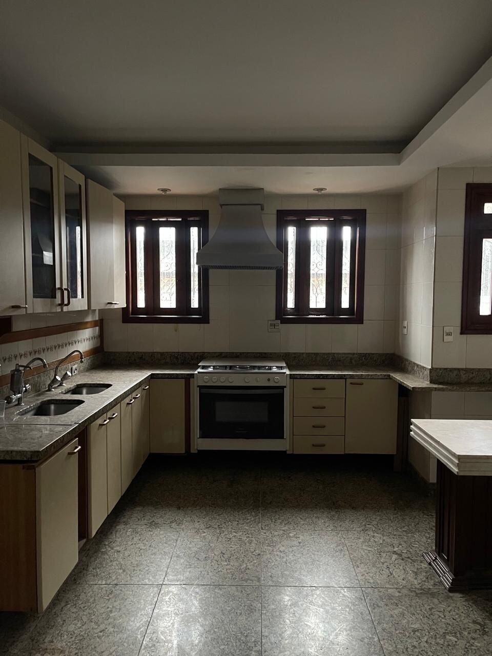 Une cuisine équipée d’une cuisinière, d’un four, de deux éviers et d’une fenêtre ornée d’une grille décorative.