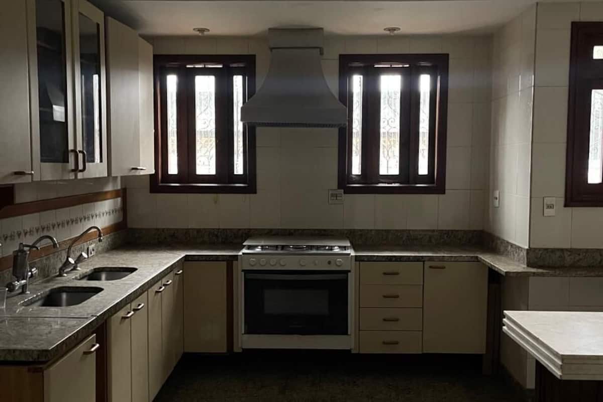 Eine Küche mit Herd, Backofen, zwei Spülen und einem Fenster mit dekorativem Gitter.