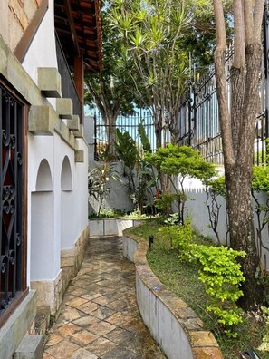 Uma trilha de pedra estreita que leva a um edifício branco com janelas em arco e um portão de metal.