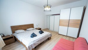 A bedroom with a bed, bedside tables, a wardrobe, and a pink sofa. - Villa Hana in Historic Stolac (Stolac)