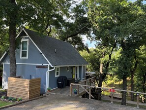A small, single-story building with a dark blue exterior, a covered porch, and a wooden deck.