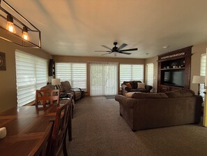 Una sala de estar con ventilador de techo, televisor y comedor con mesa y sillas.