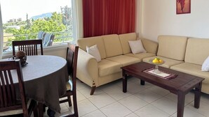 A living room with a sofa, a coffee table, and a dining table. - Θάλασσα Thea (Kavala Paleo tsifliki)