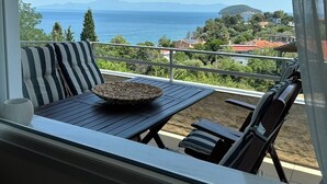 A balcony with a view of the sea and mountains, striped outdoor furniture, and a woven basket on the table. - Θάλασσα Thea (Kavala Paleo tsifliki)