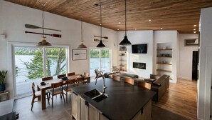 A modern kitchen with a large island, wooden ceiling, and a view of the outdoors. - Chalet 2025 sur lac Barron navigable Spa, quai, 4 rooms -14 pers - Laurentians (Gore)