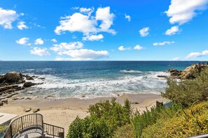 A beach with rocky terrain, a staircase, and a clear view of the ocean.