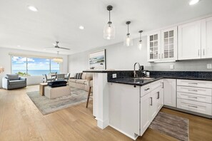 A modern kitchen with white cabinets, a granite countertop, and pendant lighting.