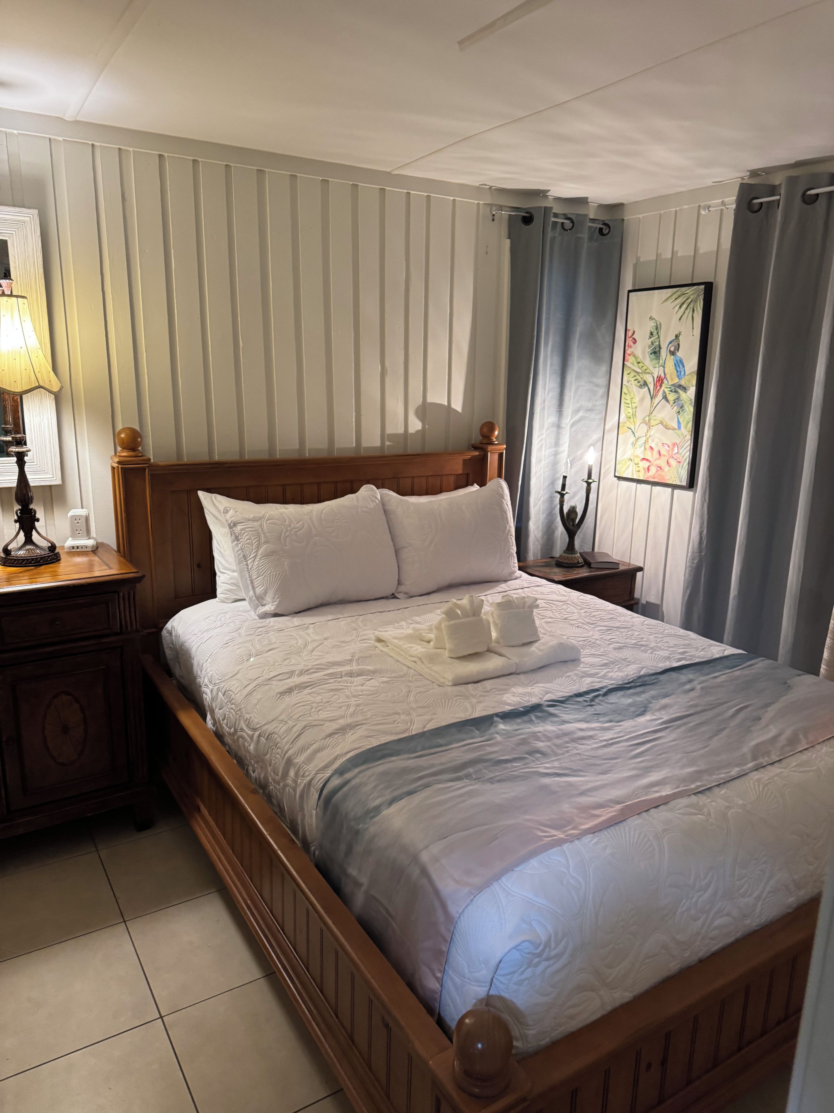 A neatly made bed with pillows, a bedside lamp, and a wall-mounted painting.