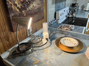 Eine Küchenarbeitsplatte mit einem Gasherd, einem Wasserkocher, einer Steckleiste und einer Dekotasse.