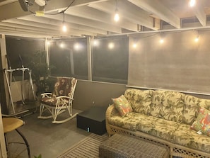 Ein Sitzbereich im Freien mit einer Couch und Sesseln, einem kleinen Tisch und Lichterketten.