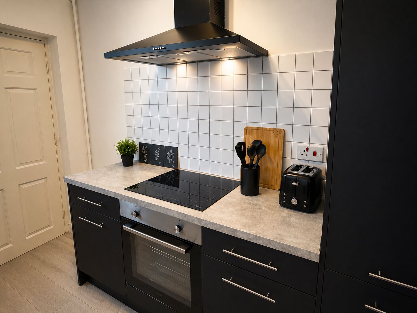 Una cucina moderna con un piano cottura nero, un forno nero, un tagliere di legno e un tostapane.
