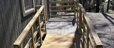 A wooden deck leading to a building with a window and a door, surrounded by trees.