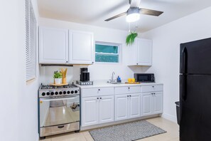 A kitchen with white cabinets, a stove, oven, microwave, and a black refrigerator. - Cozy Palm Beach Stay 5min Downtown Pets OK (West Palm Beach)