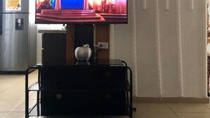 A living room with a flat-screen TV on a black stand, a refrigerator, and a tiled floor. - Spacious 3-bedroom apartment in tranquil Panamá with AC (Panamá)