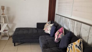 A living room with a sectional sofa, a ceiling fan, a decorative wall piece, and a window with blinds. - Spacious 3-bedroom apartment in tranquil Panamá with AC (Panamá)