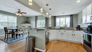 A modern kitchen with white cabinets, a granite countertop, and a built-in dishwasher. - Norfolk 5BR Family Home Near Ocean View Beach (Norfolk)