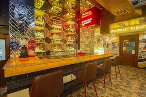 Eine Bar mit einem gemusterten Boden, einer Theke mit Hockern und einer Wand mit Flaschenregalen.
