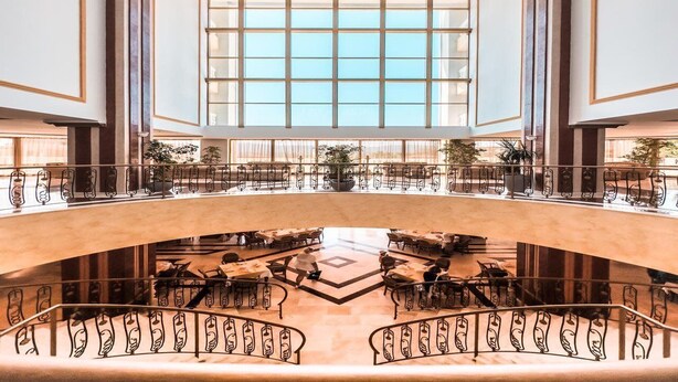 A spacious atrium with a central open area, multiple levels with seating, and a large window providing natural light. - Marina Royal Palace (Sozopol)