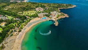 An aerial view of a coastal resort with a beach, swimming pools, and a marina. - Marina Royal Palace (Sozopol)