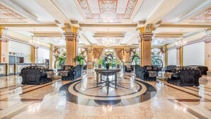 A grand lobby with a central round table, ornate columns, and a chandelier. - Marina Royal Palace (Sozopol)