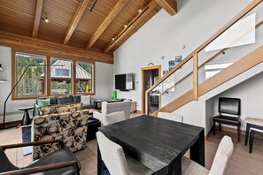 A modern interior with a wooden ceiling, a dining area, and a staircase.