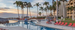 A pool area with lounge chairs, palm trees, and a building with balconies. - Relaxing beachside resort and spa, close to San Jose. (San José del Cabo)
