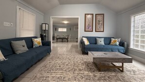 A living room with two sofas, a coffee table, and a dining area in the background. - Private Gated Montrose Cottage Near FIFA & Downtown (Houston)