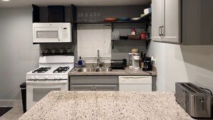 A compact kitchen with a gas stove, microwave, sink, and a toaster. - Private Gated Montrose Cottage Near FIFA & Downtown (Houston)