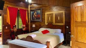 Um quarto com painéis de madeira, uma cama, uma mesinha de cabeceira, um abajur e um quadro na parede.