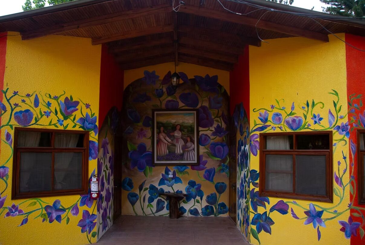 A building with vibrant yellow walls and purple floral murals.