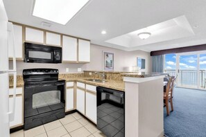 Eine moderne Küche mit Mikrowelle, Backofen und Geschirrspüler, ein Essbereich mit Tisch und Stühlen sowie ein Balkon mit Blick.
