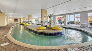 Une piscine intérieure avec un bord carrelé, des bouées jaunes flottantes et une statue centrale.
