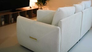 Een moderne woonkamer met een witte bank, een flatscreen televisie, een lamp en een schilderij aan de muur.