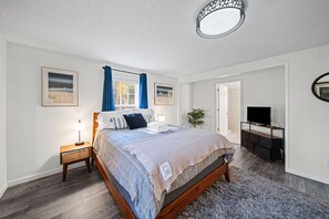 Een slaapkamer met een bed, nachtkastjes, een tv-meubel en een plafondlamp.
