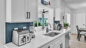 A modern kitchen with a built-in blender, a double sink, and a ceiling fan. - Spacious Family Getaway Near AMI Beaches! Bikes, Beach Gear, Pets & Sleeps 8 (Bradenton)