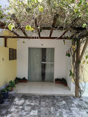 A covered entrance with a glass door, potted plants, and a tiled floor. - Apartment in a prime location on Coroa Vermelha beach, in a gated community. (Santa Cruz Cabrália)