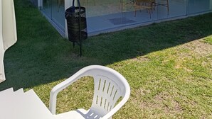 A modern building with a glass enclosure, outdoor seating, and a grassy area. - Apartment in a prime location on Coroa Vermelha beach, in a gated community. (Santa Cruz Cabrália)