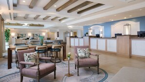 Eine Hotelhalle mit Empfangstresen, Sitzgelegenheiten und einem Essbereich.