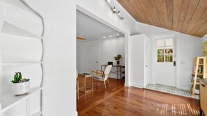 A spacious room with wooden flooring, white walls, and a ceiling with exposed beams.