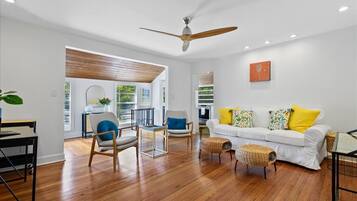 Un salon moderne avec un canapé blanc, un plancher en bois et un ventilateur de plafond.