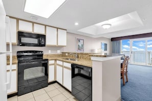 Eine moderne Küche mit Mikrowelle, Backofen und Geschirrspüler, ein Essbereich mit Tisch und Stühlen sowie ein Balkon mit Blick.
