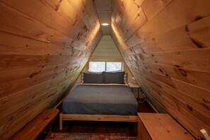 A small, wooden attic bedroom with a single bed, a window, and a sloped ceiling. - Whimsical A-Frame | Secluded Feel, Close to Town (Murphy)