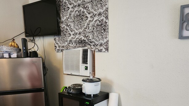 A compact kitchen with a refrigerator, microwave, stove, and a small table with a placemat.