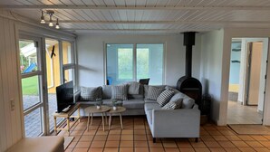 Ein modernes Wohnzimmer mit einer Eckcouch, einem kleinen Couchtisch, einem Kamin und großen Fenstern.