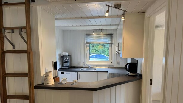 Eine kleine Küche mit integriertem Kaffeeautomaten, einem Fenster mit Blick und einer Holzleiter.