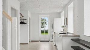 Een moderne keuken met een ingebouwde wasmachine, een spoelbak en een raam met uitzicht op groen.