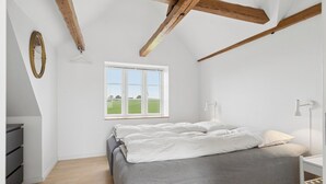 Een slaapkamer met een bed, een raam, een bureau en een spiegel.