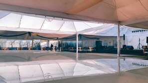 Una amplia zona cubierta con carpas, un escenario y asientos.