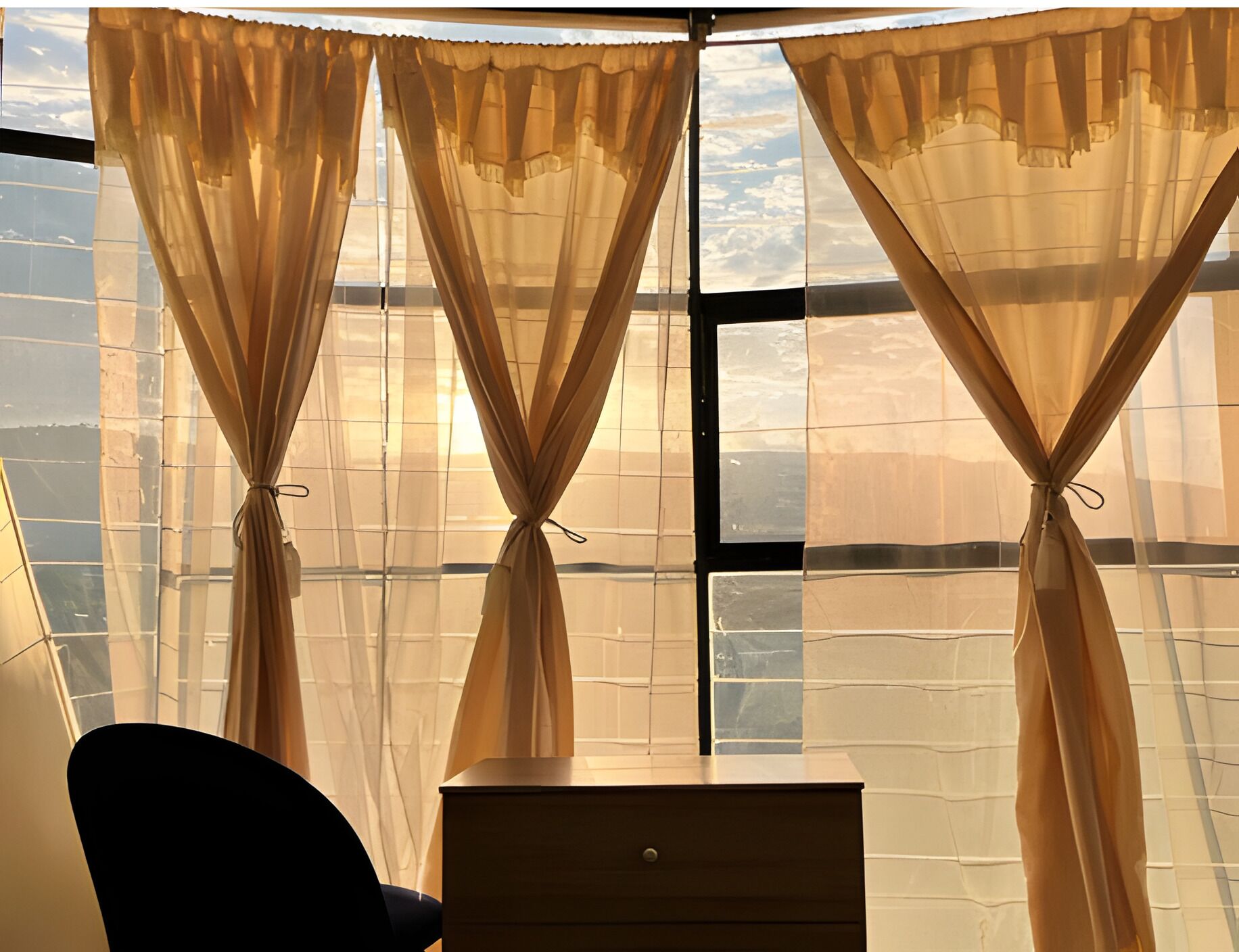 Una habitación con un ventanal grande, un escritorio y una silla.
