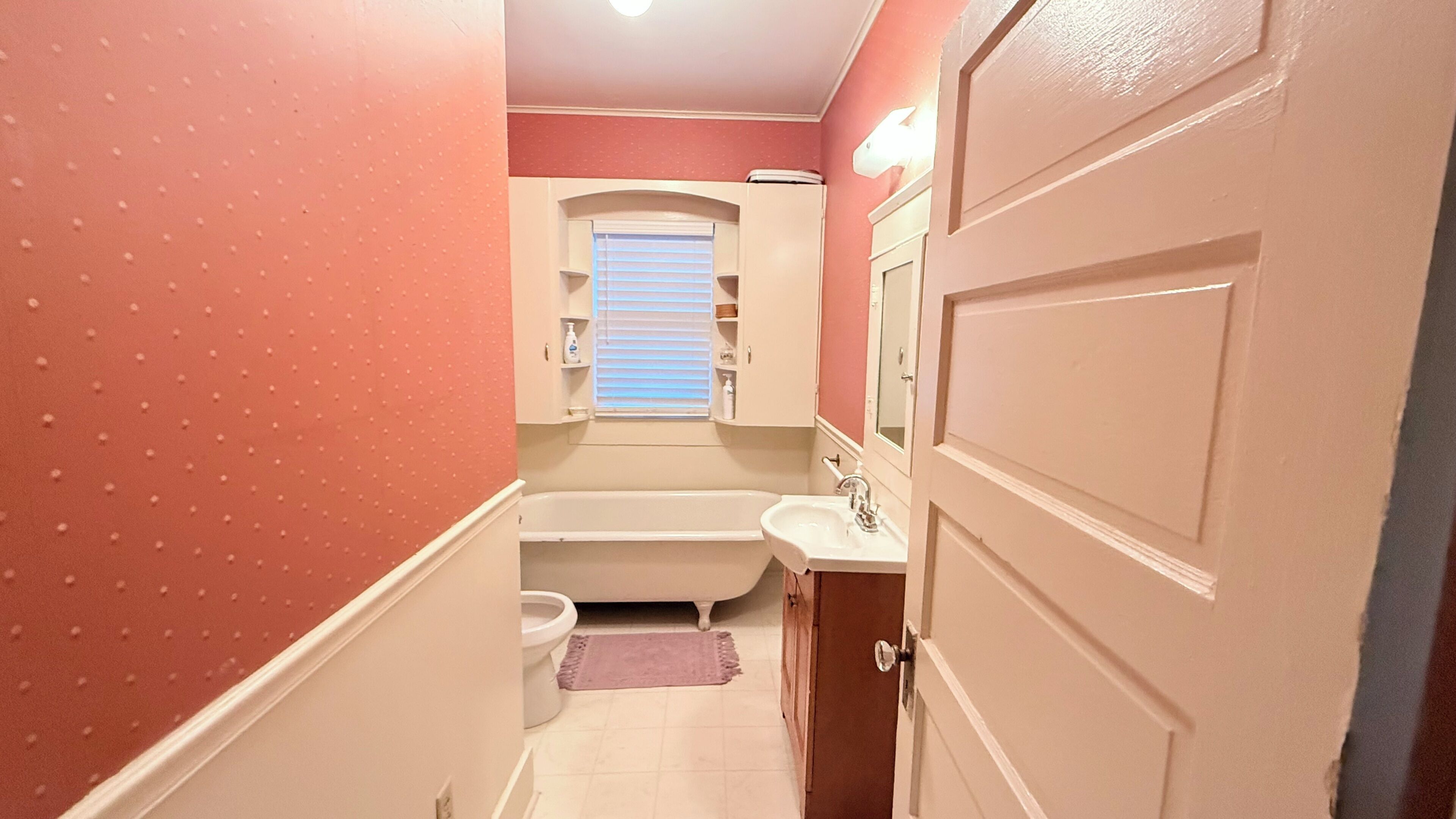 A narrow bathroom with a bathtub, toilet, and sink.